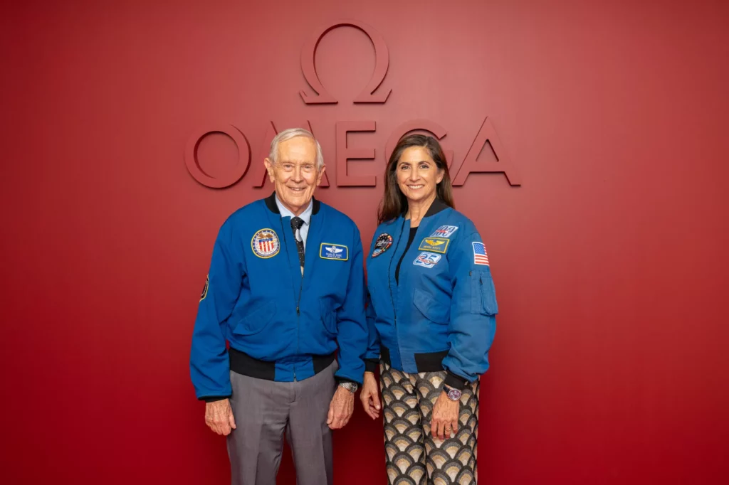 Portrait of Charlie Duke and Nicole Stott, NASA astronauts with red Omega background