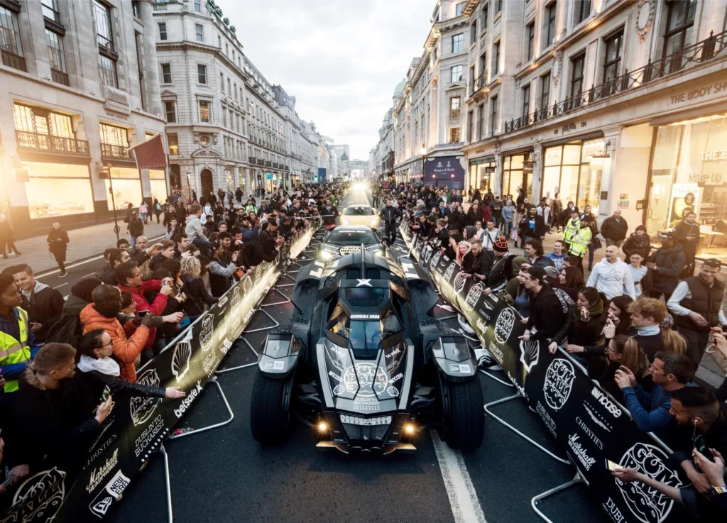 Gumball 3000 sports cars being cheered on by crowed in city