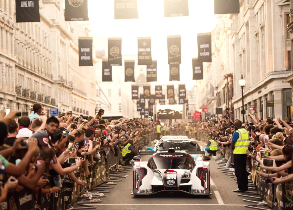 Gumball 3000 sports cars being cheered on by crowed in city