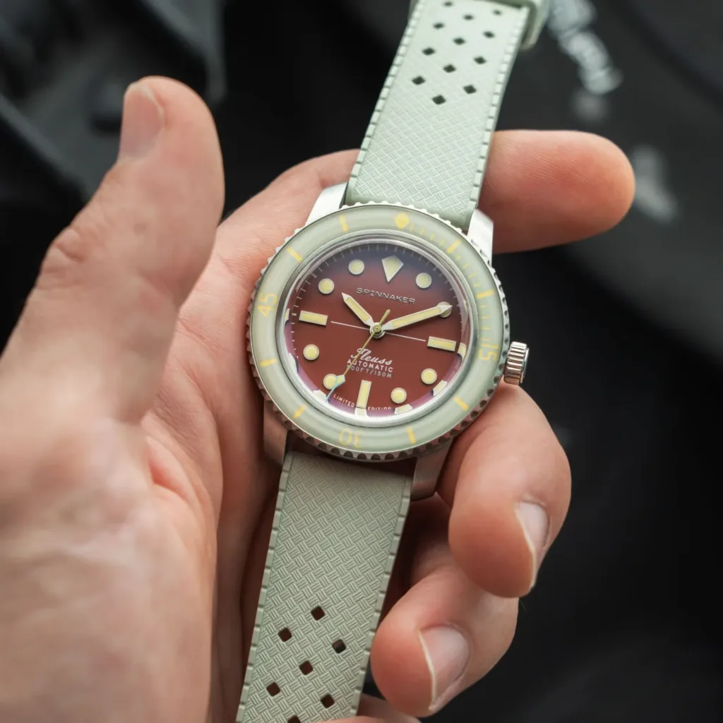 Spinnaker Introduces Fleuss 40 Automatic - 145th with coral red dial on rubber strap in palm of hand